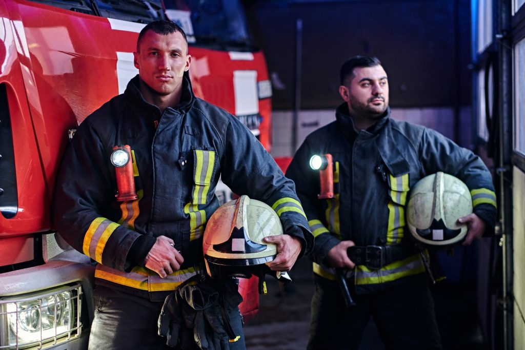 two firemen standing near the fire truck at night in a fire depot 1.jpg